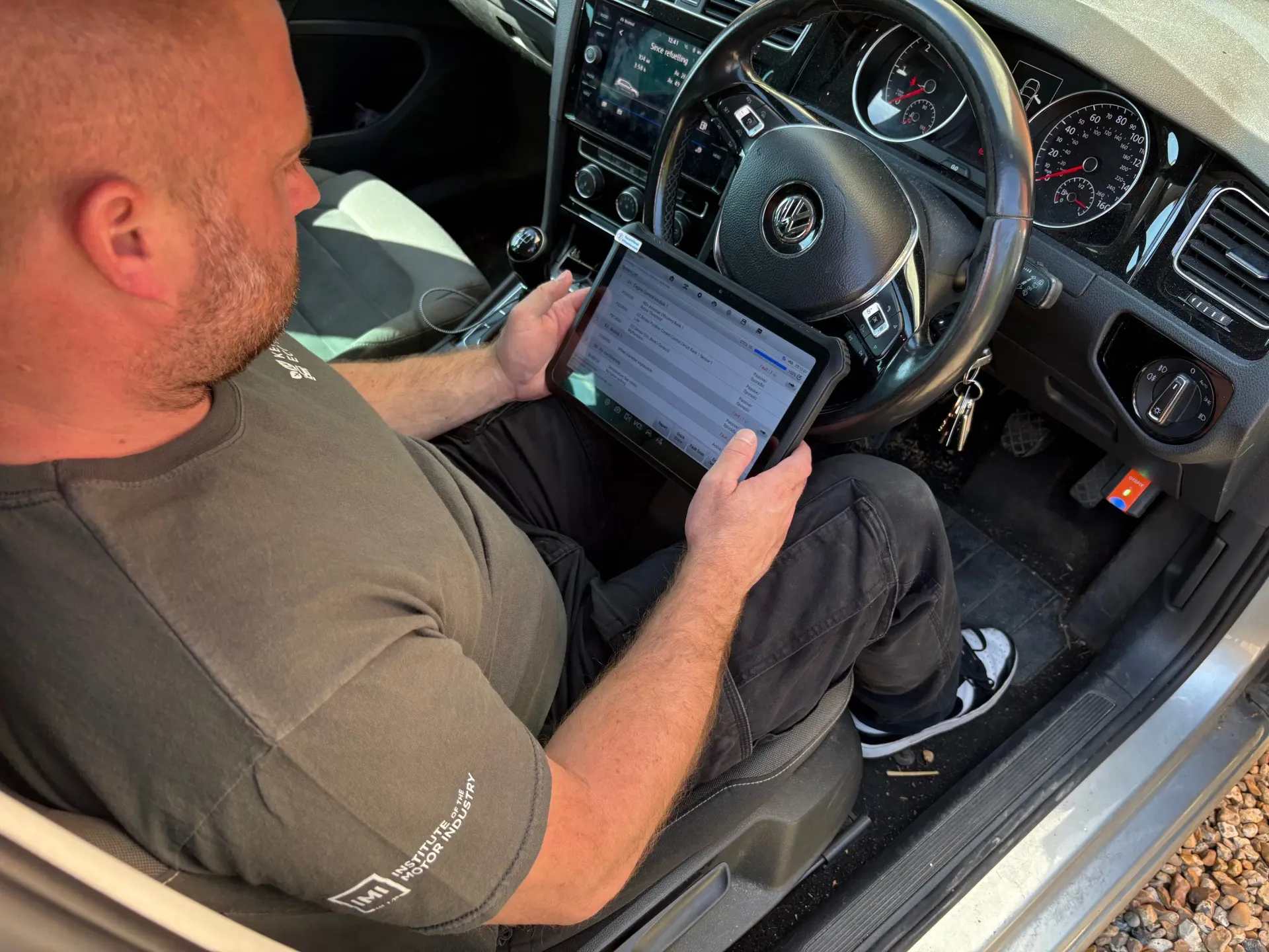 Kent Eco Tuning technician running dealer-level diagnostics with a tablet on a Volkswagen